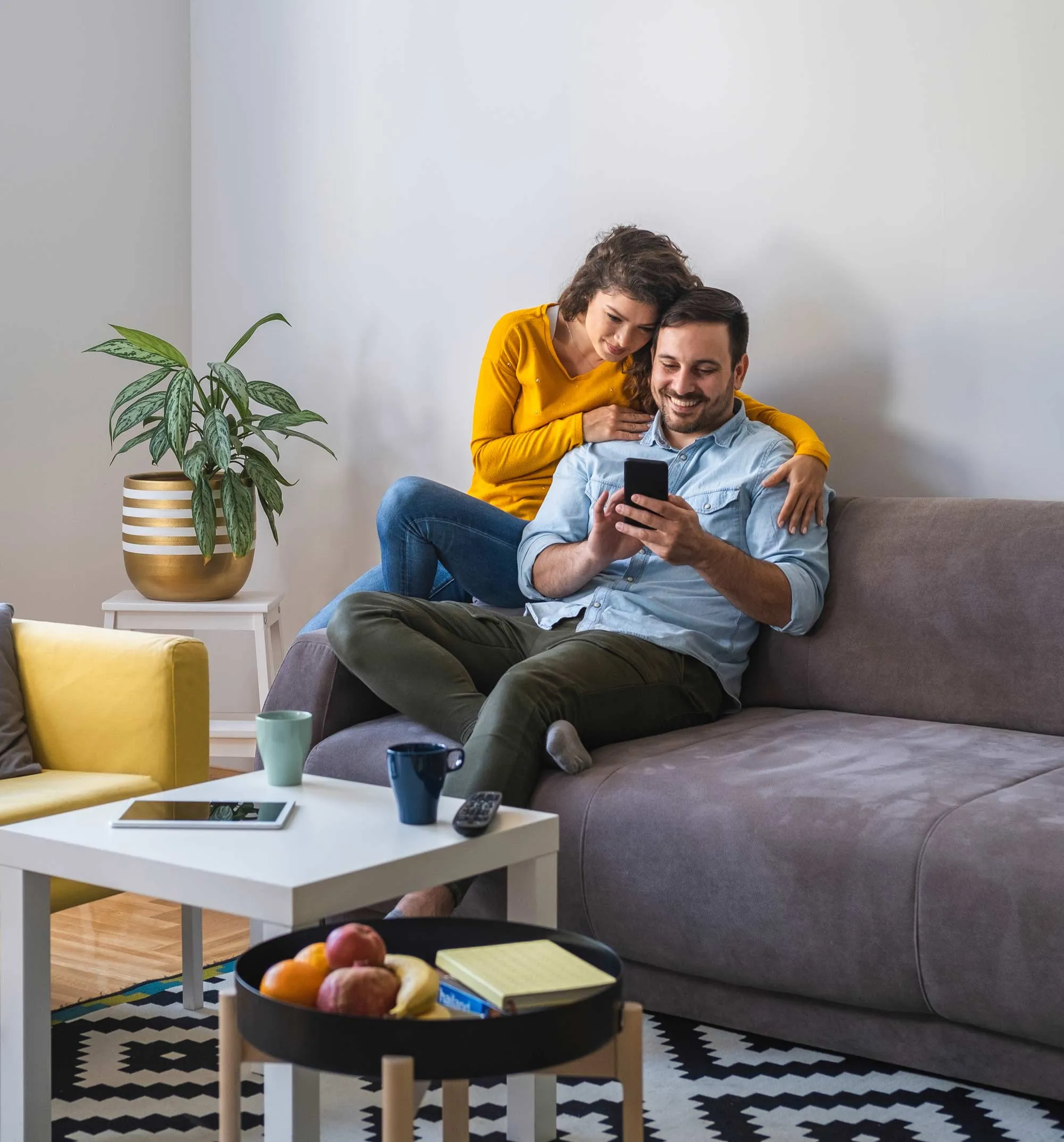 Coppia sul divano di casa che guarda lo smartphone